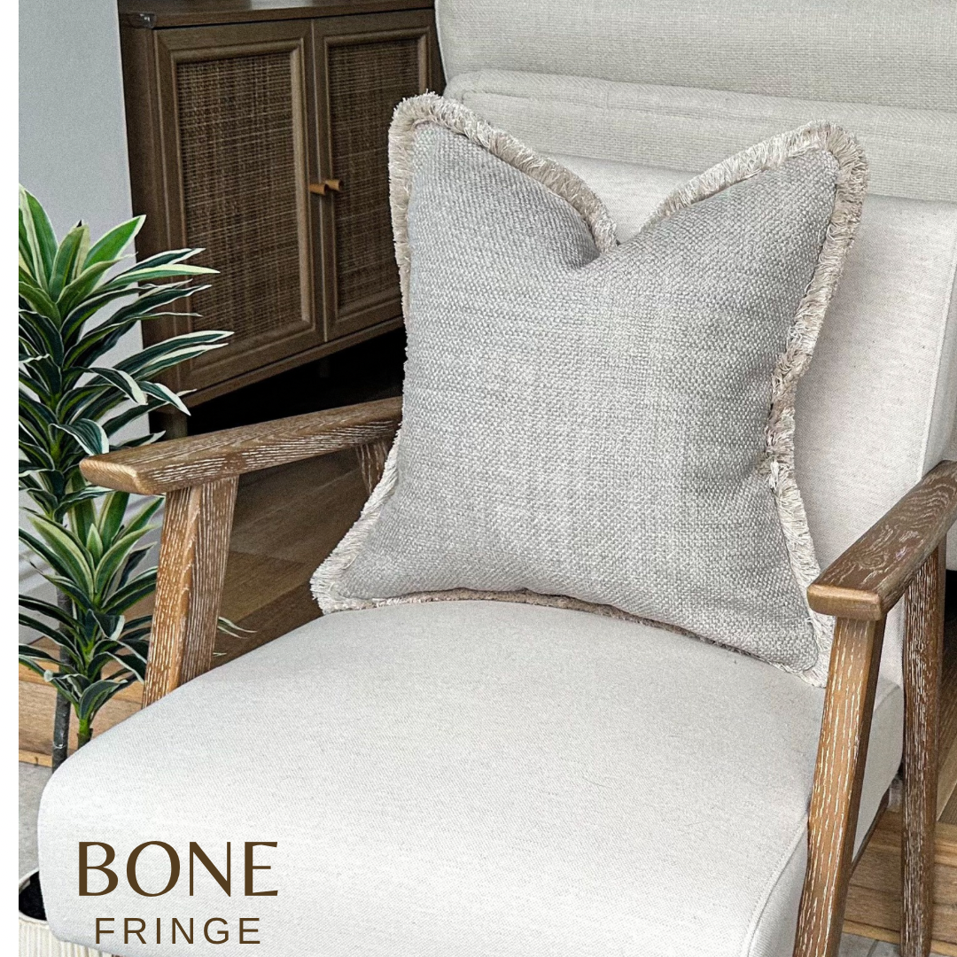 Grey beige textured pillow cover with fringed edge.