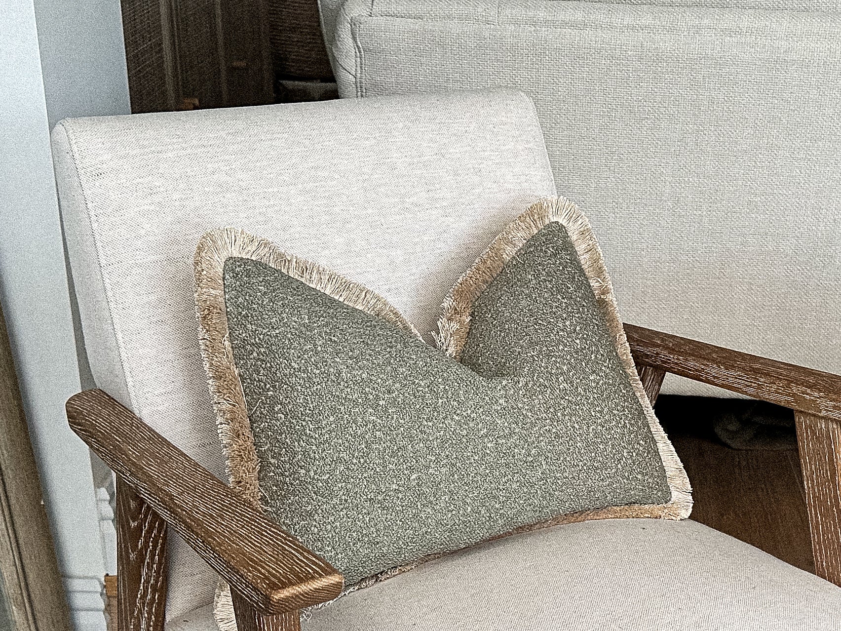 Sage green textured boucle pillow with fringe.