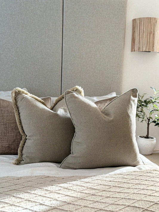 Cosy scatter cushion in beige with textured trim layered on bedding.