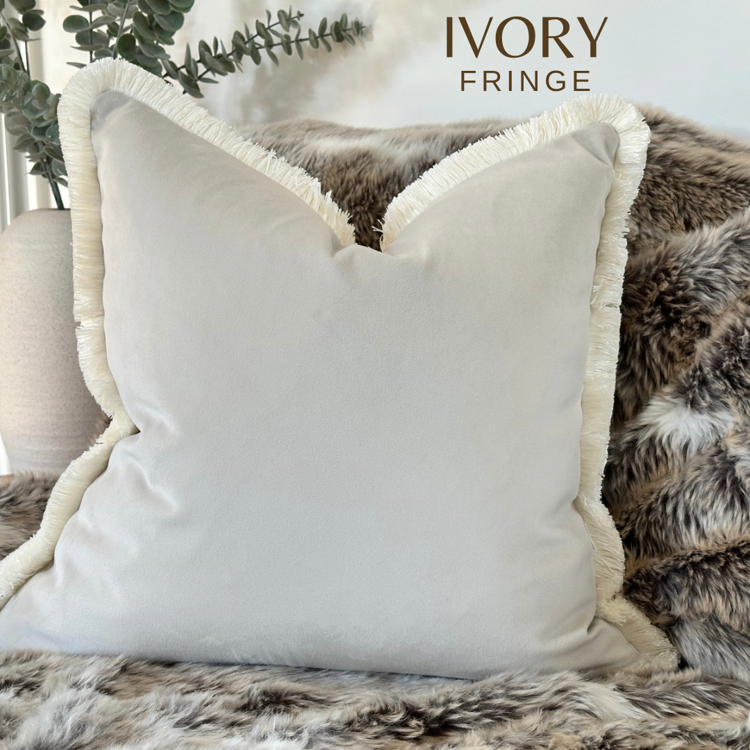 Ivory velvet cushion cover with fringe trim.