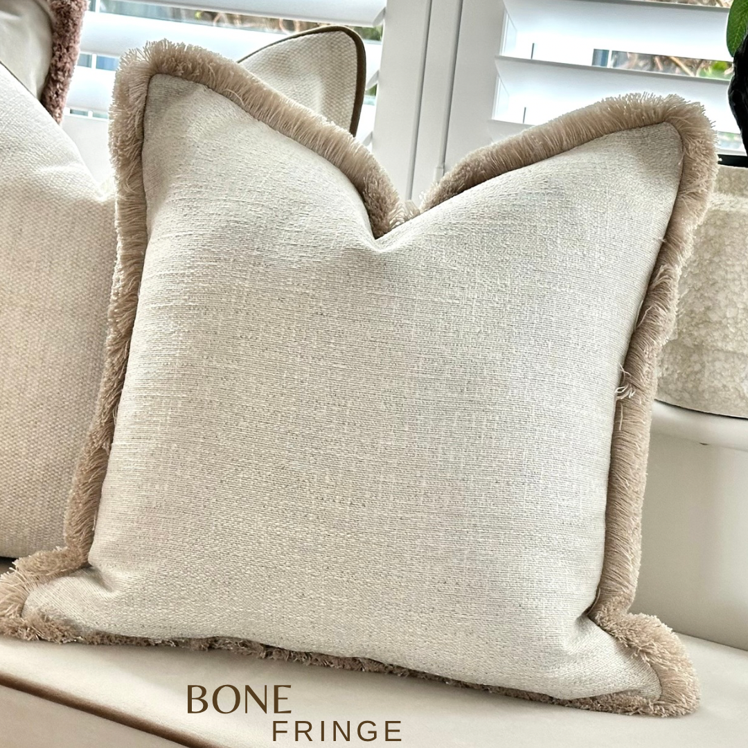 Textured ivory fringed cushion.