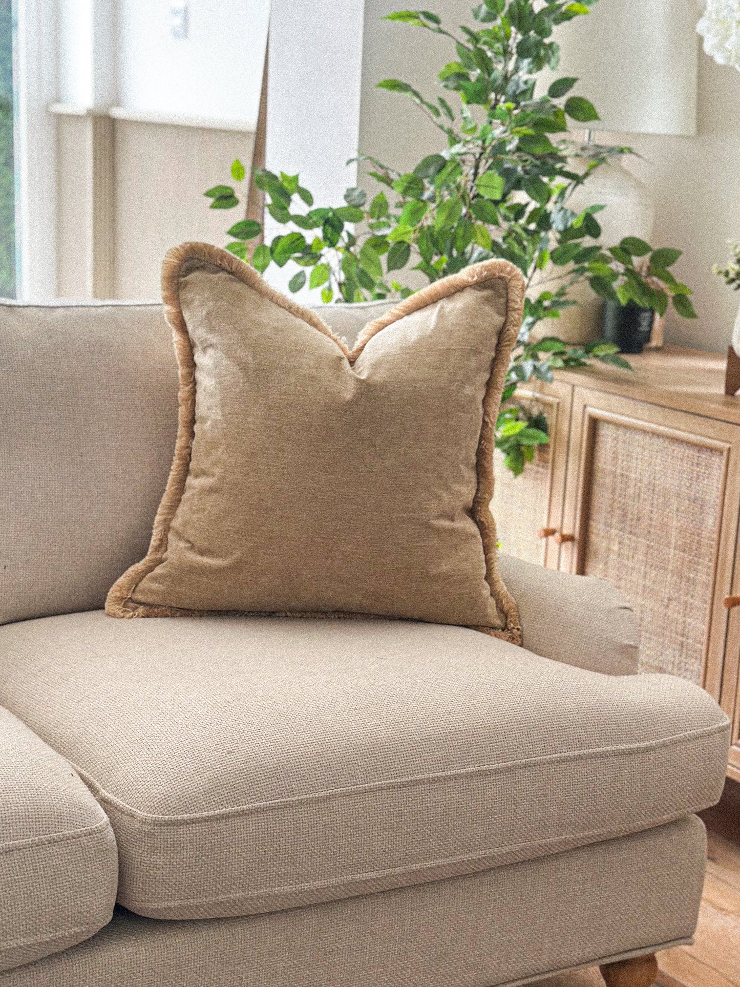 Warm caramel cushion with fringe trim on a neutral sofa.