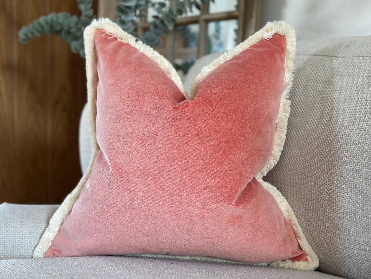 Peach ink pillow with fringe trim.