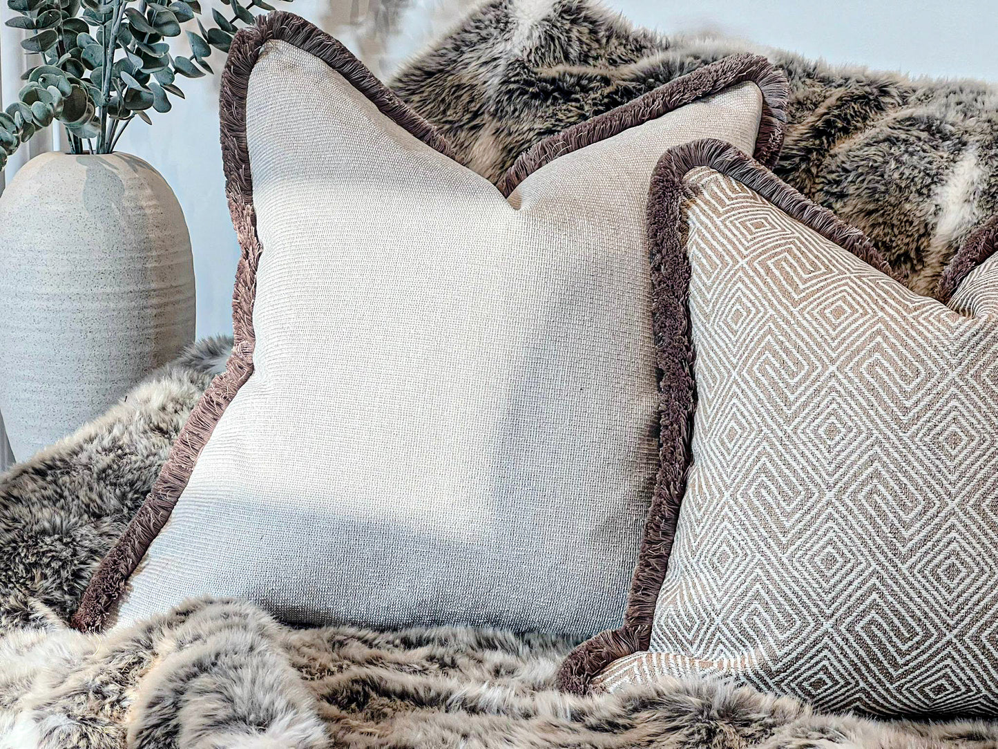 Textured grey beige cushion cover with beige fringe trim.