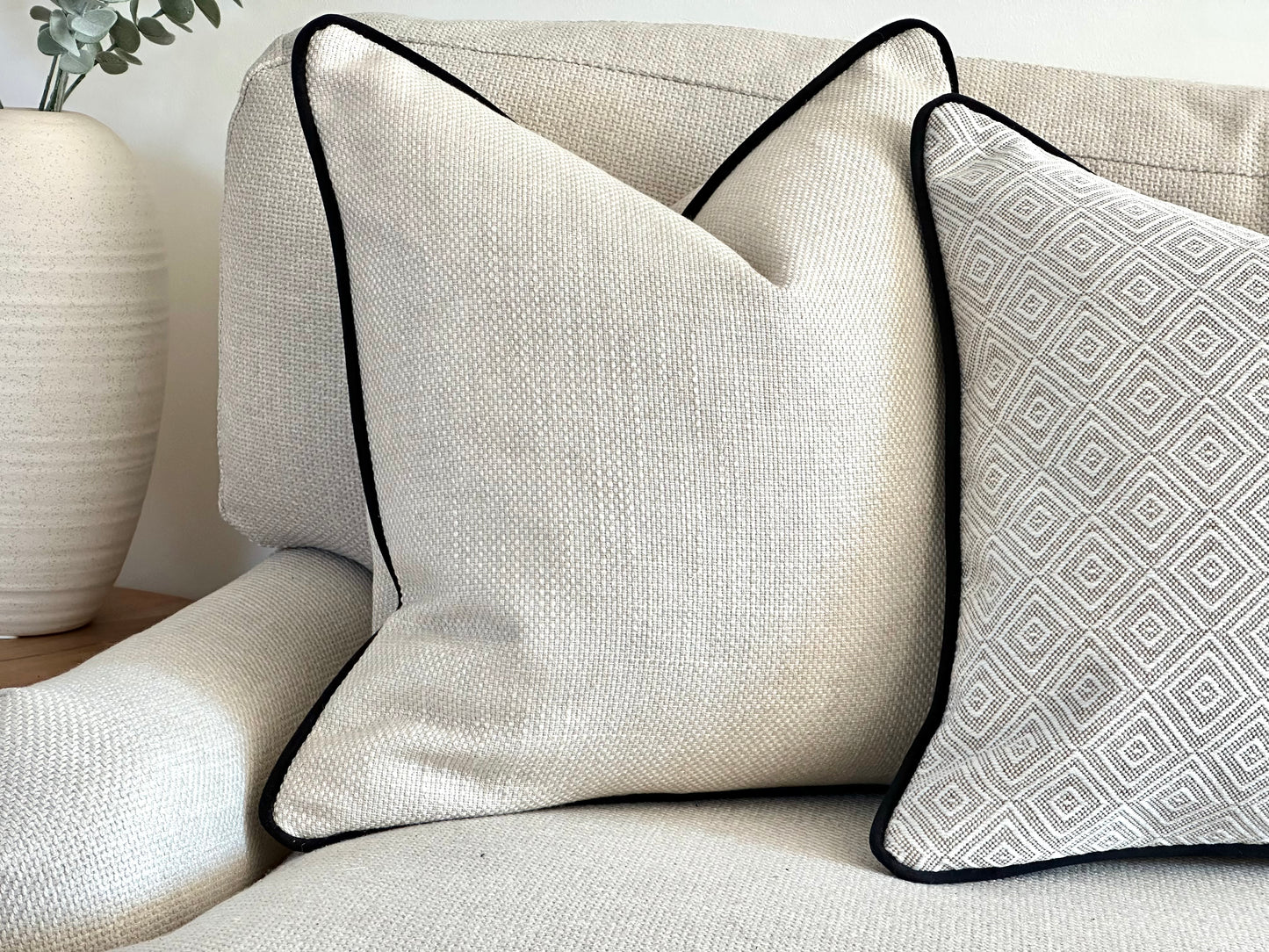 Textured Cream cushion cover with black piping on a neutral sofa in a modern neutral living space.