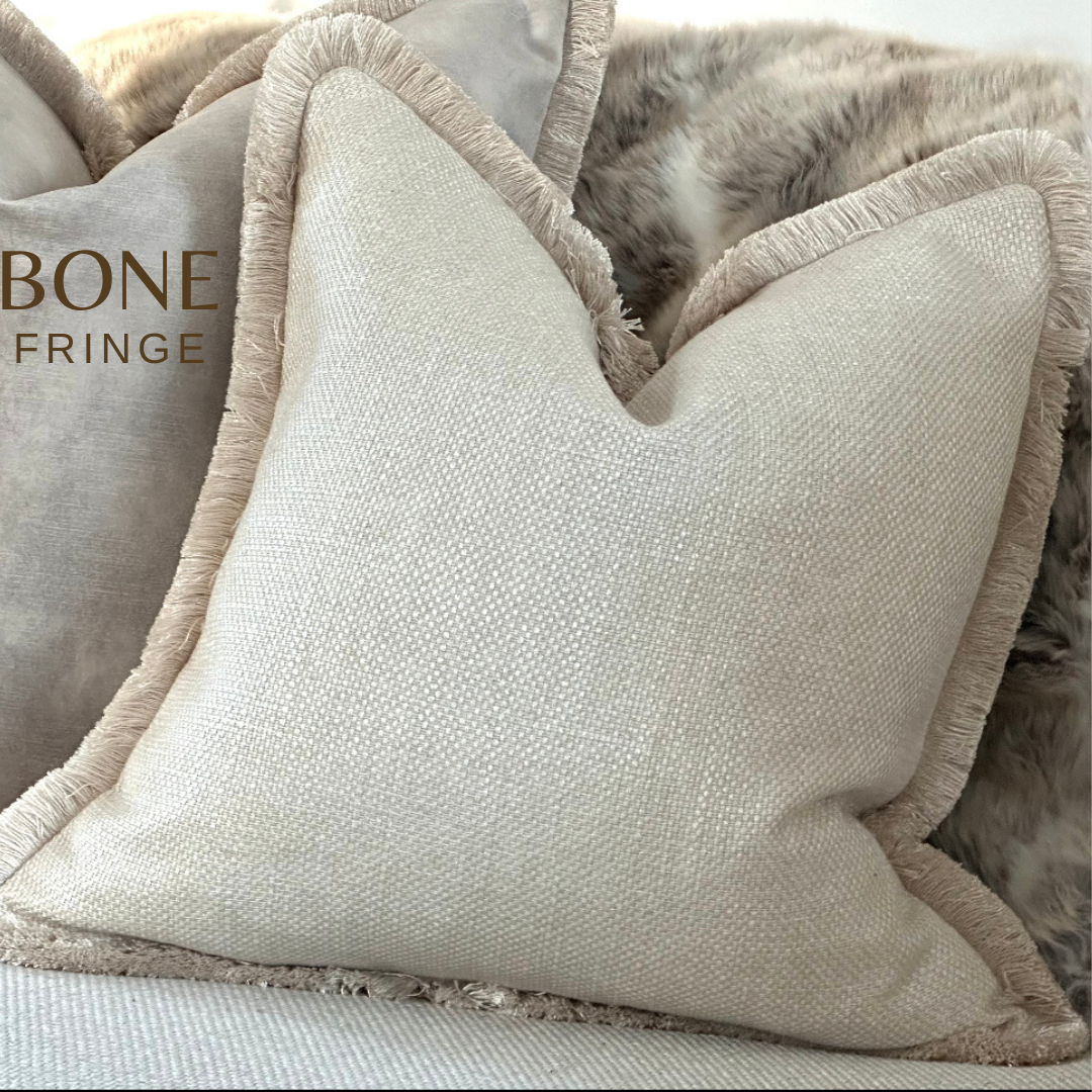 Premium neutral-toned cushion featuring soft, woven fabric and sophisticated fringe detailing, adding a timeless luxury feel to any space.