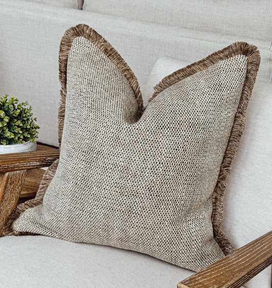 Luxury textured beige cushion cover with fringe.