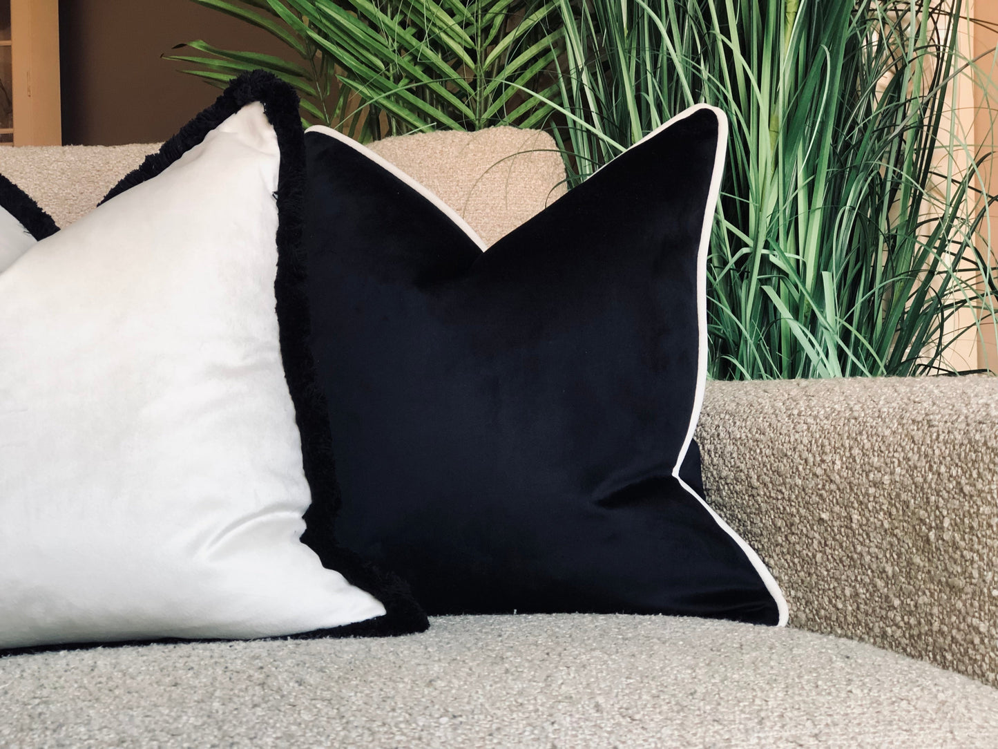 Black velvet cushion with white piping trim.