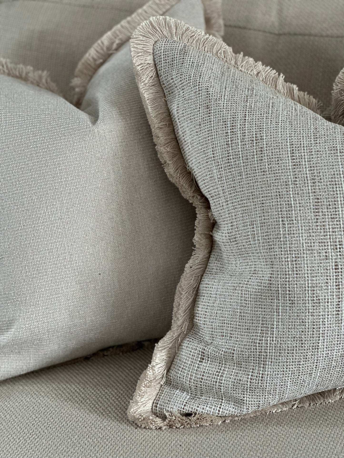Neutral textured cushion with fluffy trim.