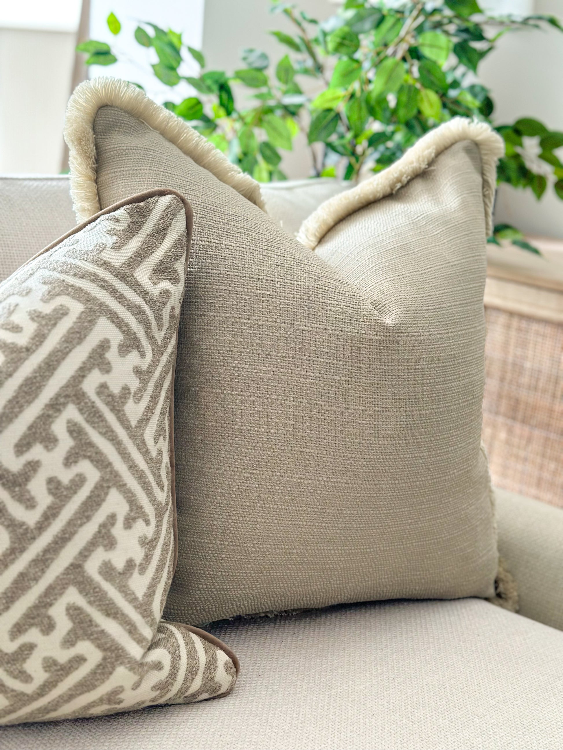 Natural woven pillow cover in a pebble tone, paired with a patterned design.
