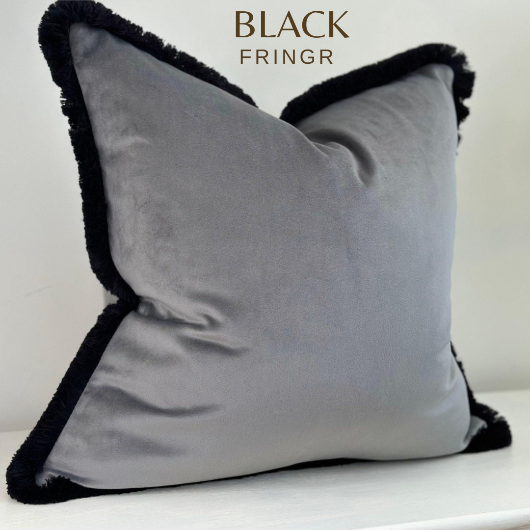Grey velvet cushion cover with black fringe trim.