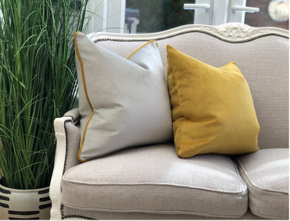 Light grey velvet cushion cover with mustard piping.