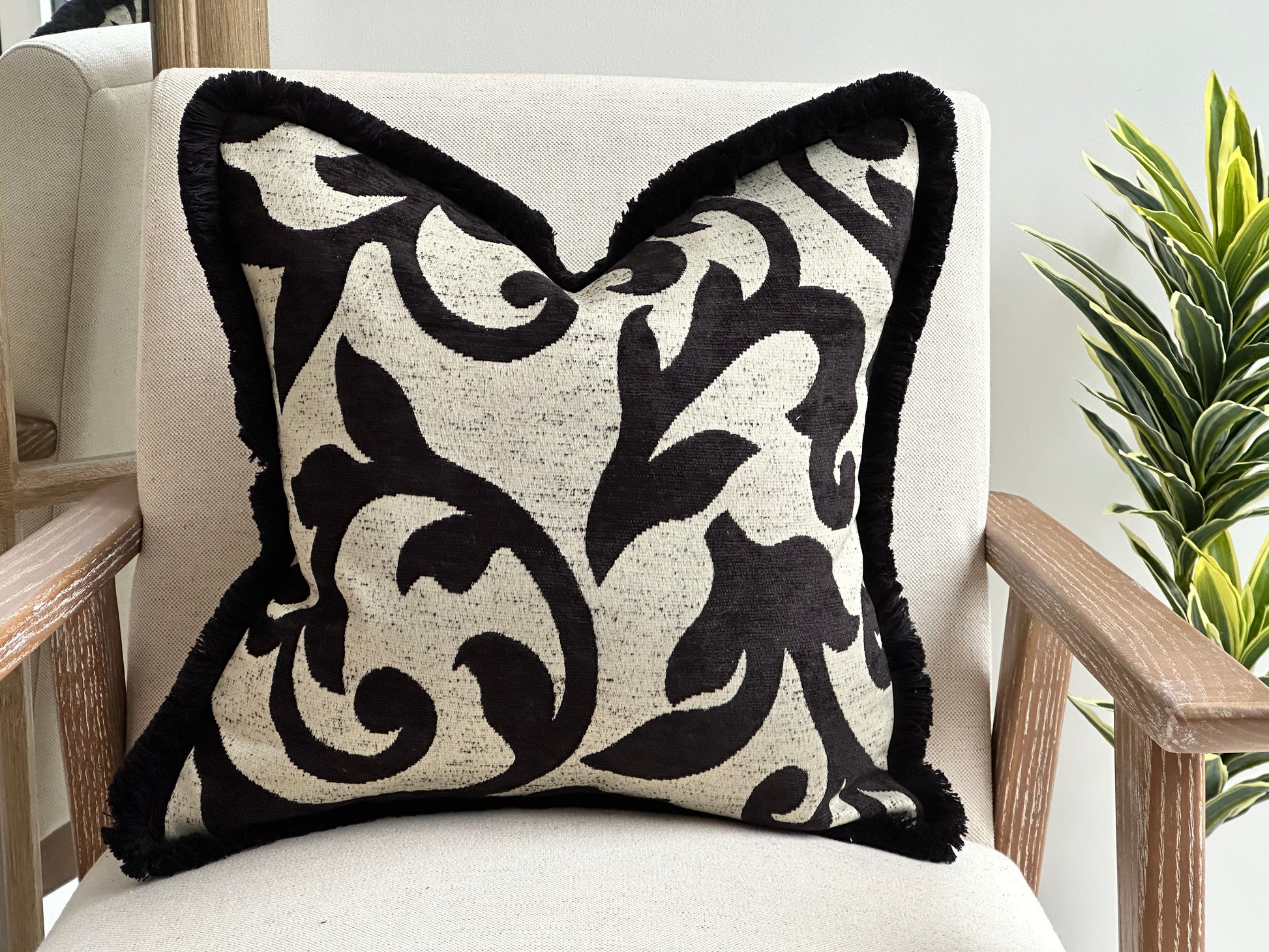 Cream cushion with black pattern and black fluffy fringe boarder