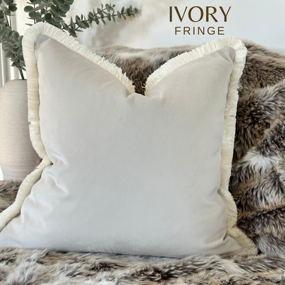 Ivory velvet cushion cover with fringe trim.