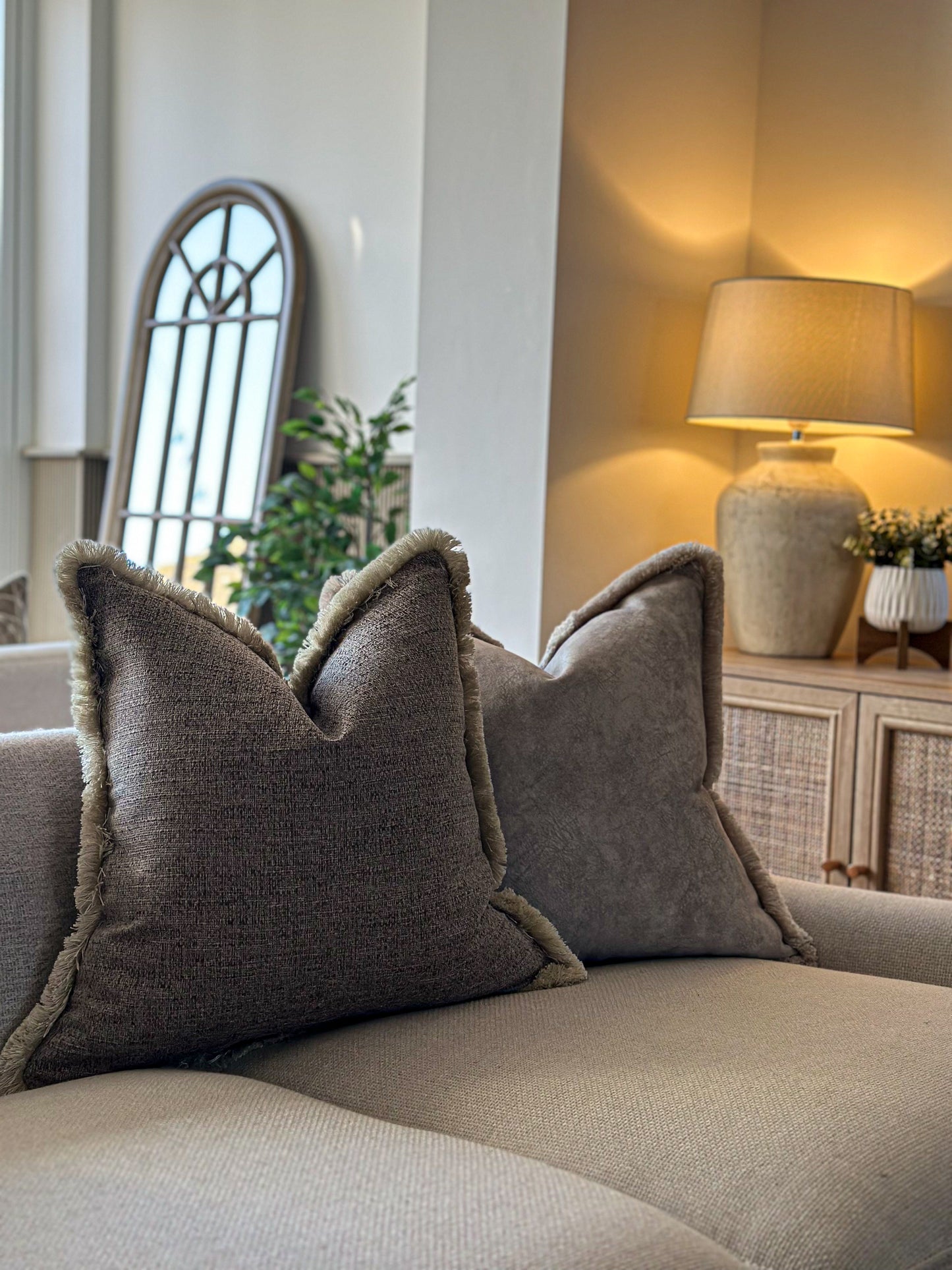 Taupe textured cushion with fringe trim.