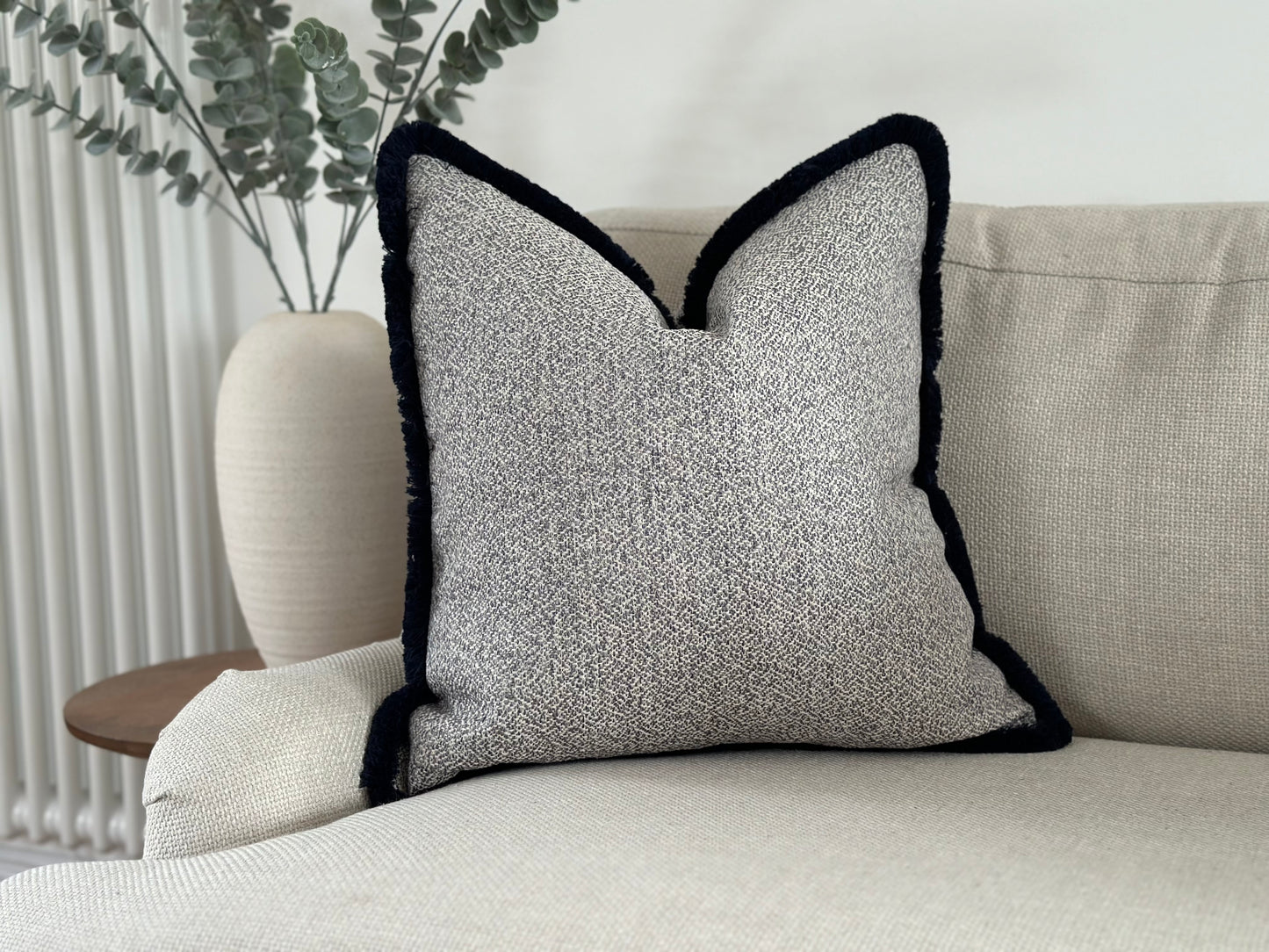 Light grey and ivory pillow with tassel trim.