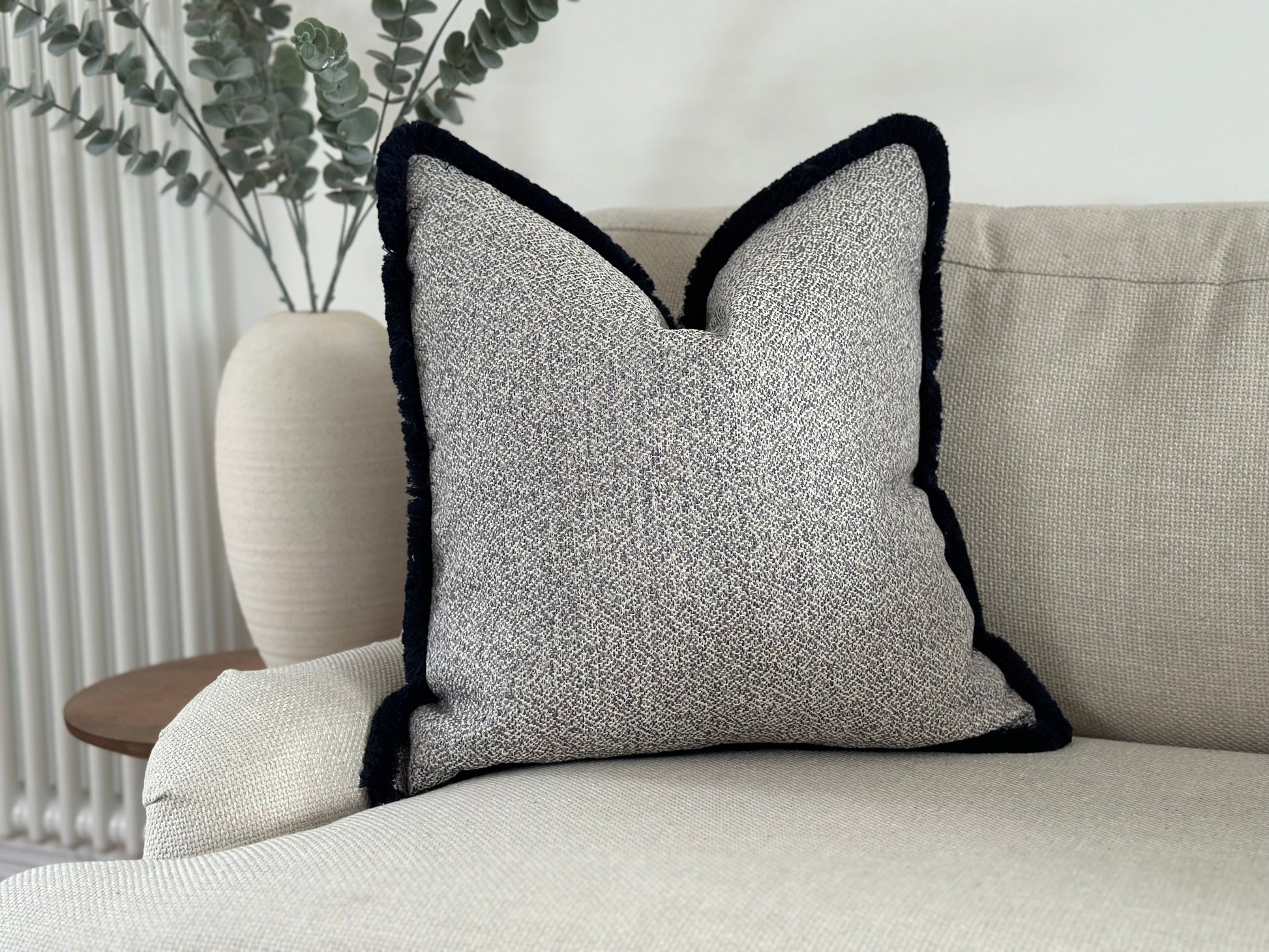 Light grey and ivory pillow with tassel trim.