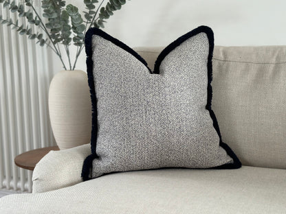 Light grey and ivory pillow with tassel trim.
