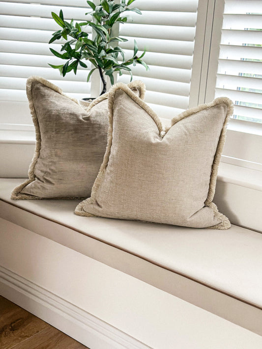 Natural cushion with fringe trim.