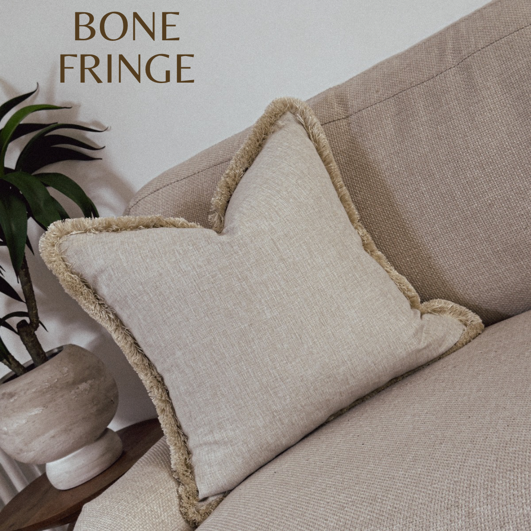 Modern farmhouse neutral cushion with fringed edge.
