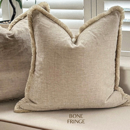 Neutral scatter cushion with fringing.