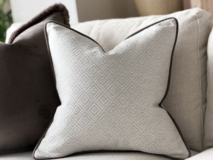 a luxury white decorative pillow with a geometric pattern, placed on a couch.