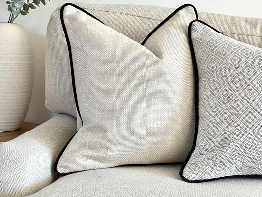 Textured Cream cushion cover with black piping on a neutral sofa in a modern neutral living space.