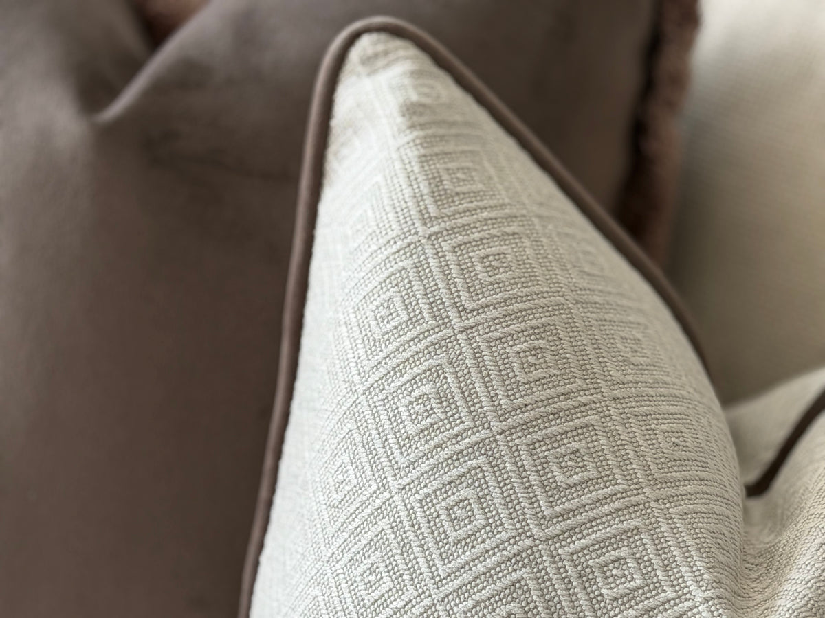 an ivory geometric cushion with brown edging