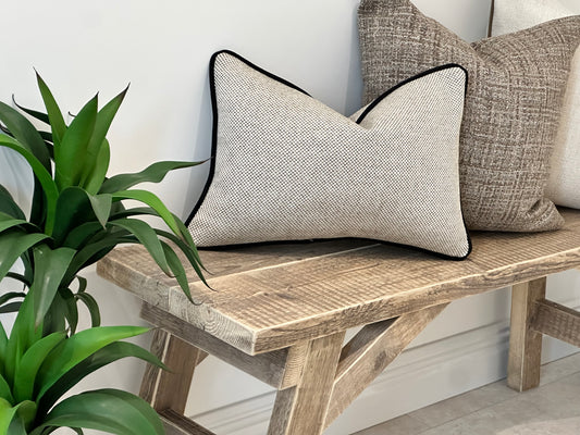 Textured cream beige rectangle cushion with black piping trim.