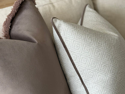 a close-up view of a sofa with two decorative pillows, one with a brown velvet texture and the other with a geometric patterned fabric.