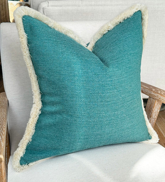 Turquoise blue textured fringed cushion.