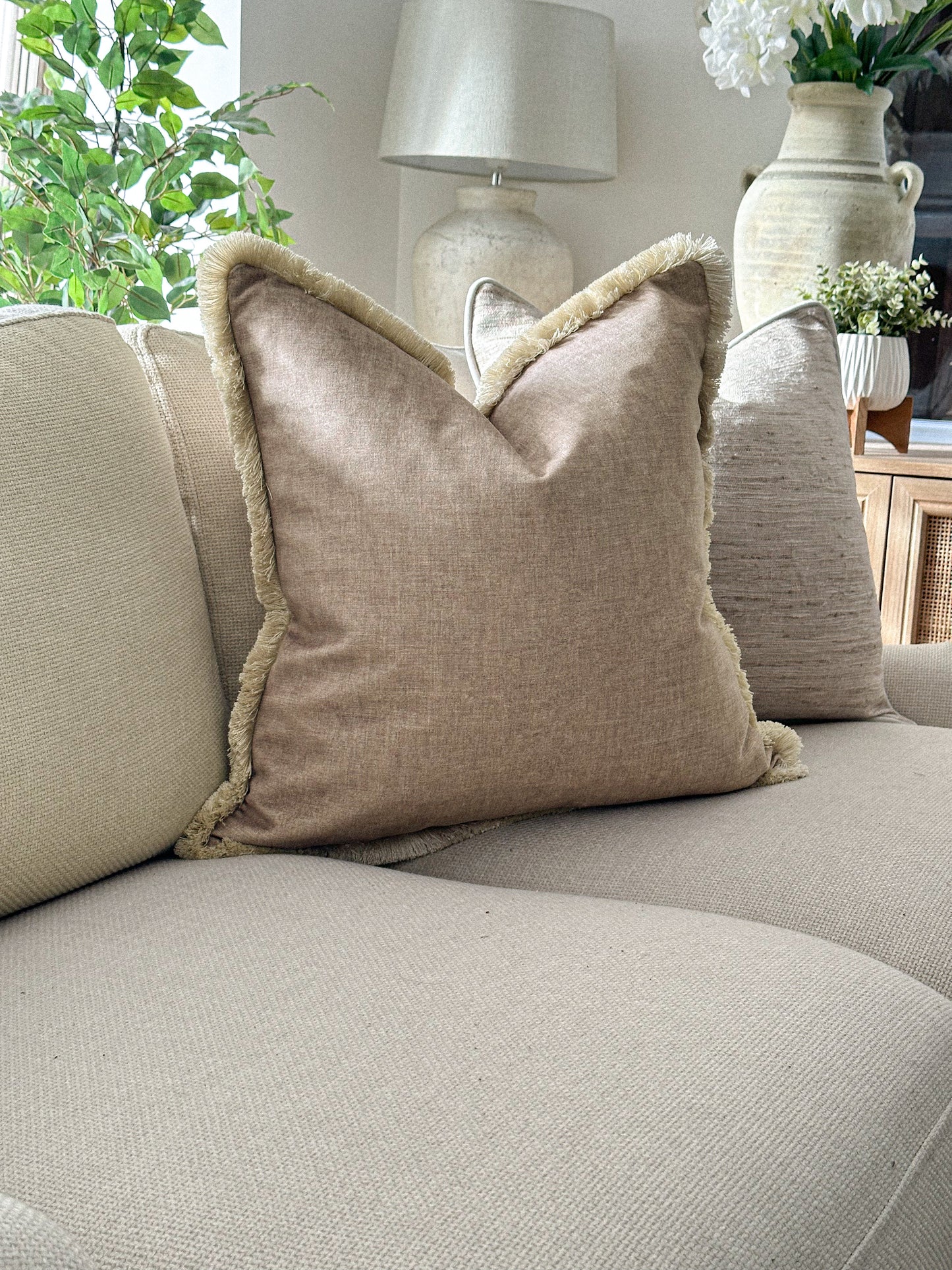 beige cushion cover styled with fringe trim for a cosy layered look.