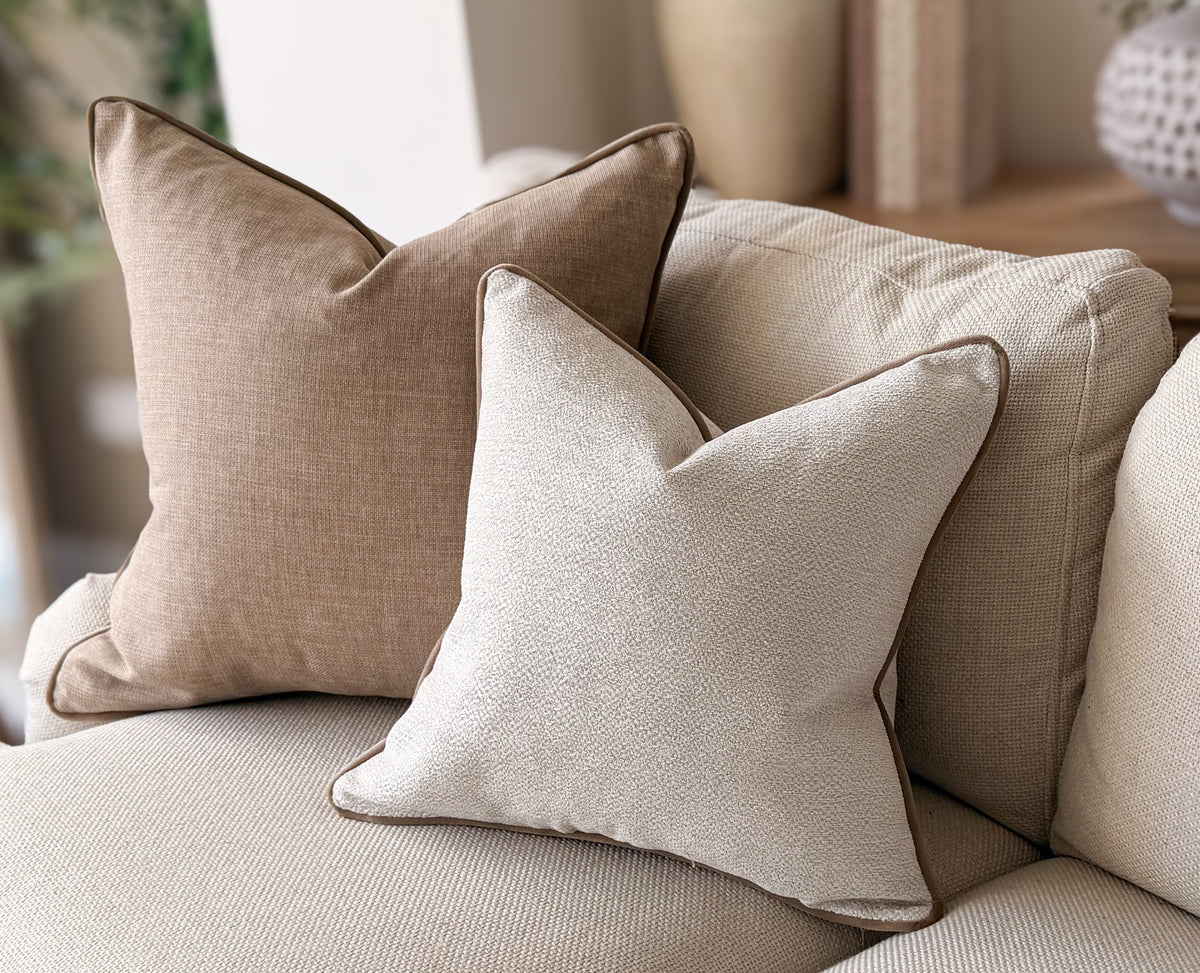 Ivory cream cushion with beige piping trim.