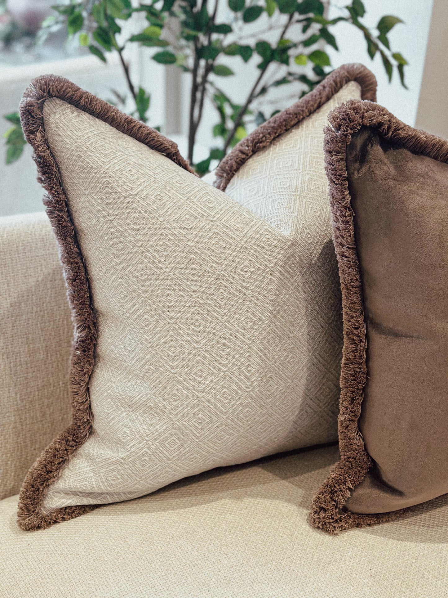 Luxury Natural geometric decorative cushion with brown trim on a beige couch.