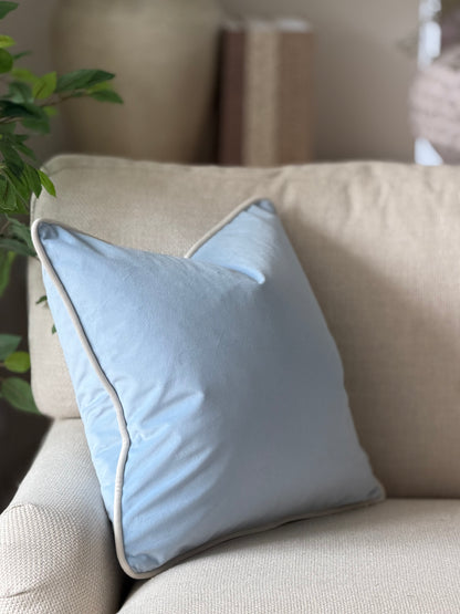 A light blue square throw pillow with a ivory white trim.