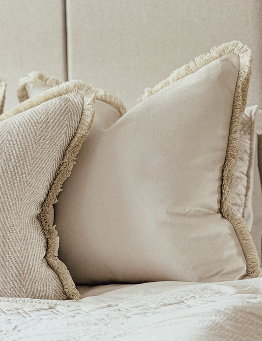 Luxury ivory velvet cushion with bone fringe trim.