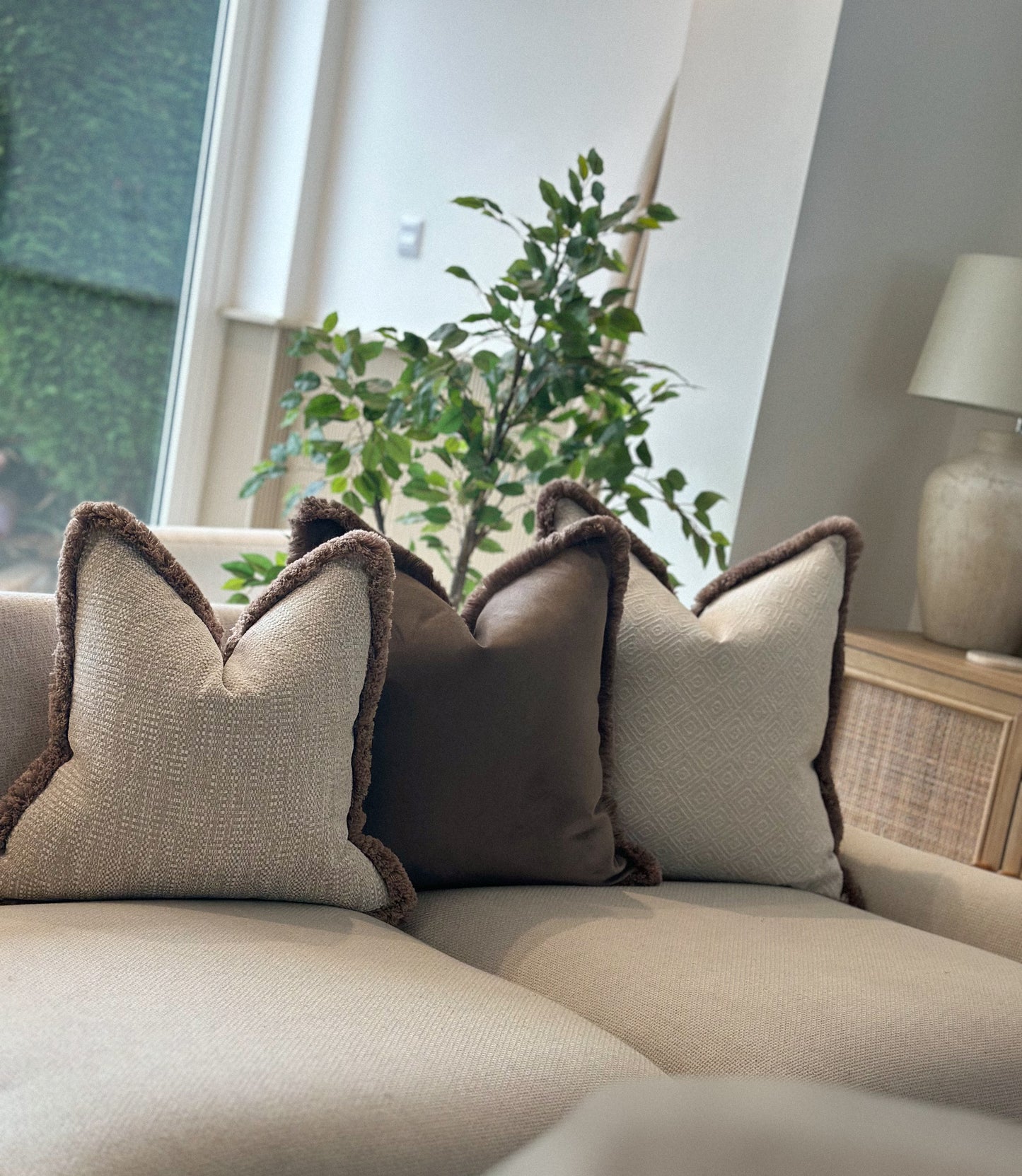 Cosy neutral decorative cushions with brown tones and fringe trim.