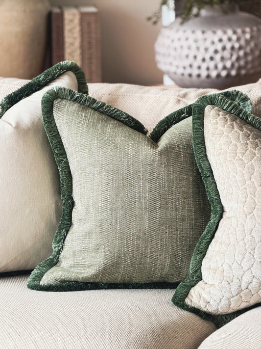 Sage green textured woven cushion with dark sage fringe trim