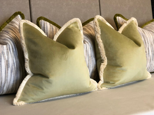 Sage green velvet cushion with cream fringe.