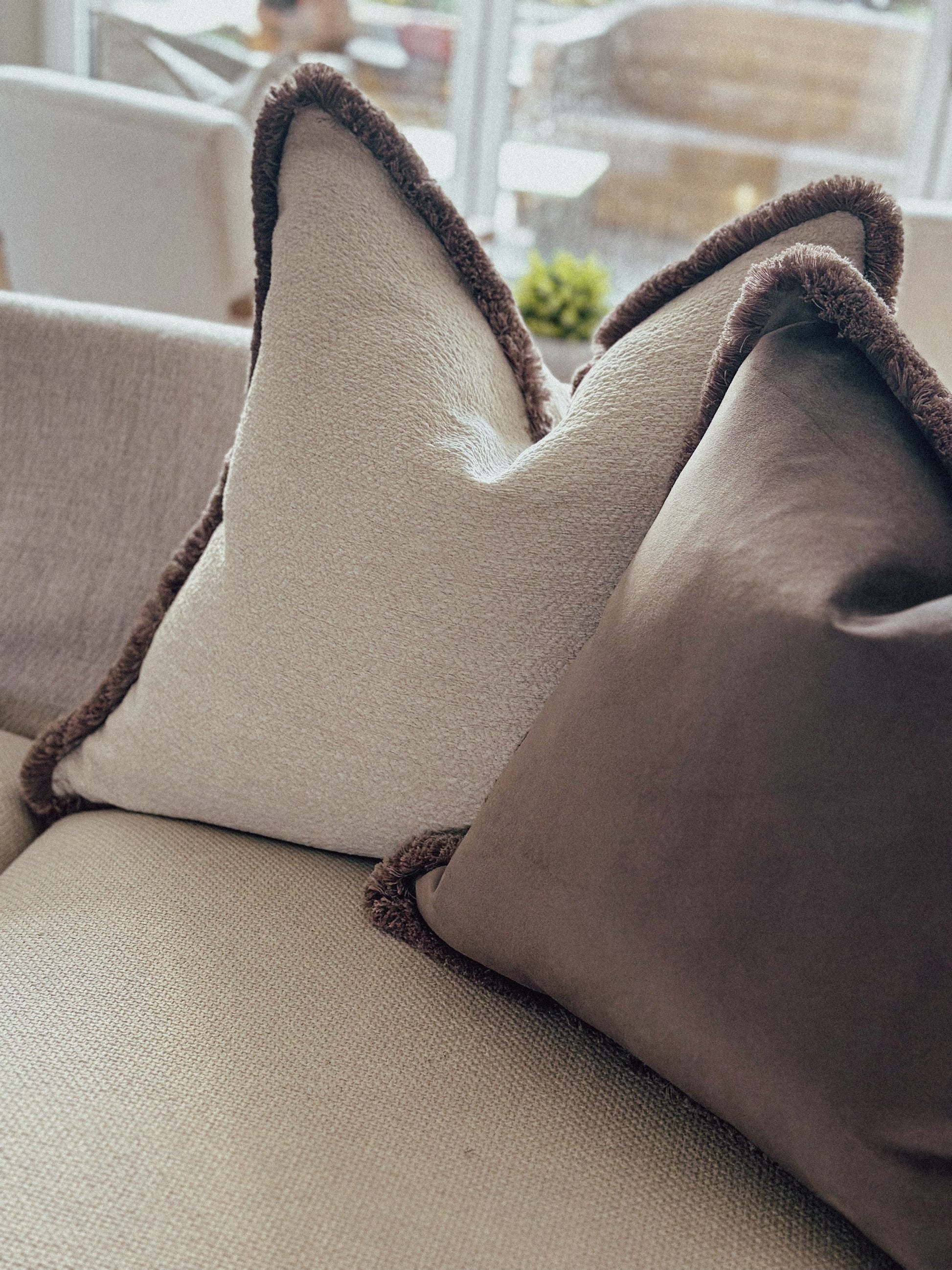 Neutral beige textured cushion with warm taupe fringe trim — perfect for cosy, earthy home décor.